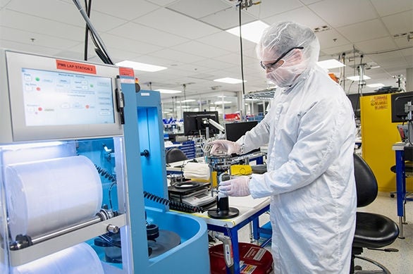 Technician operating equipment in cleanroom lab