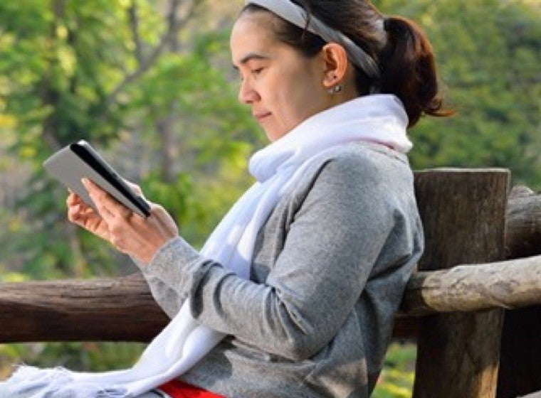 Woman sitting on a bench and reading from her tablet