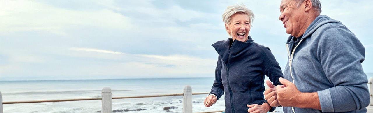 Old couple running on beach track.