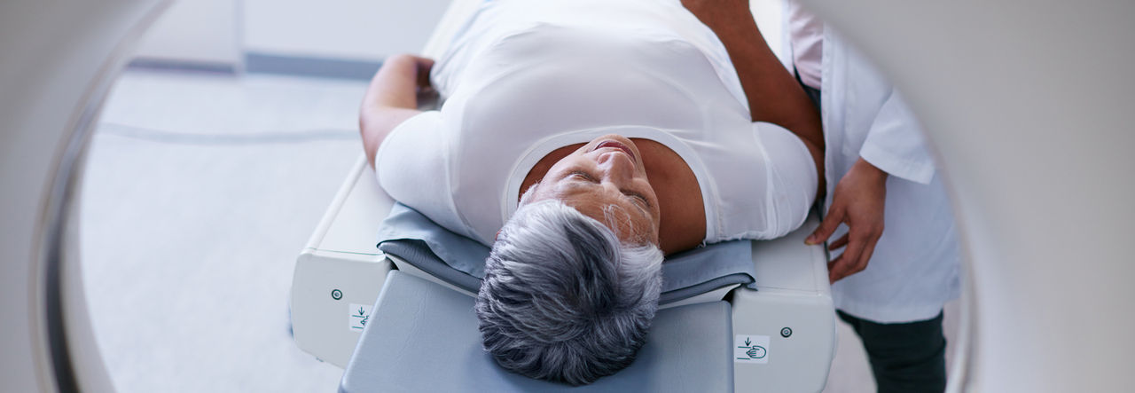 Female old patient lying on MRI bed.