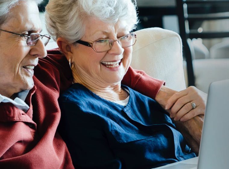 couple sitting on couch viewing laptop